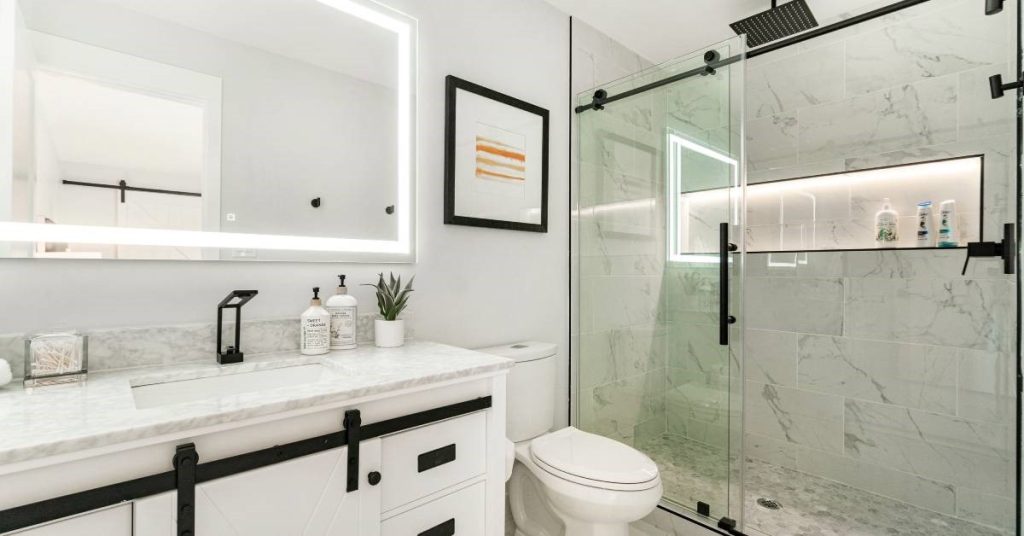 A completed residential bathroom renovation project that features a modern tub-less shower with sliding glass doors.