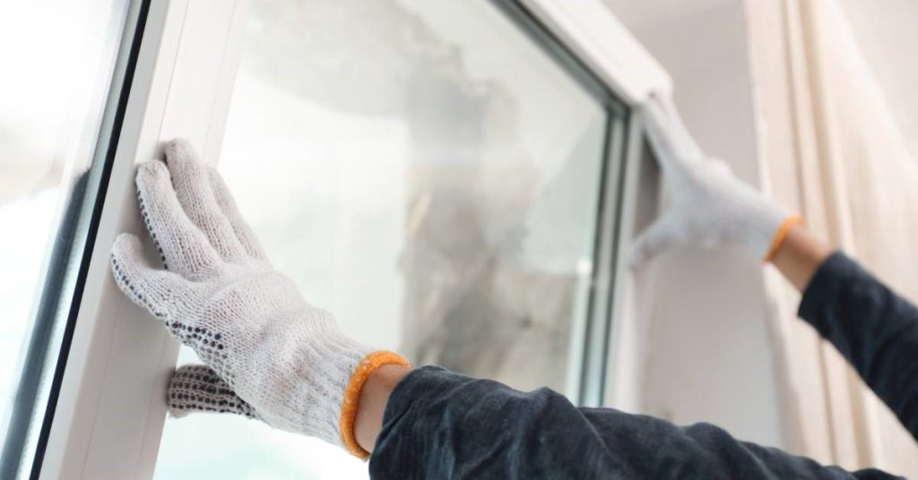 A gloved professional contractor installaing a brand new annealed glass window for his residential client.