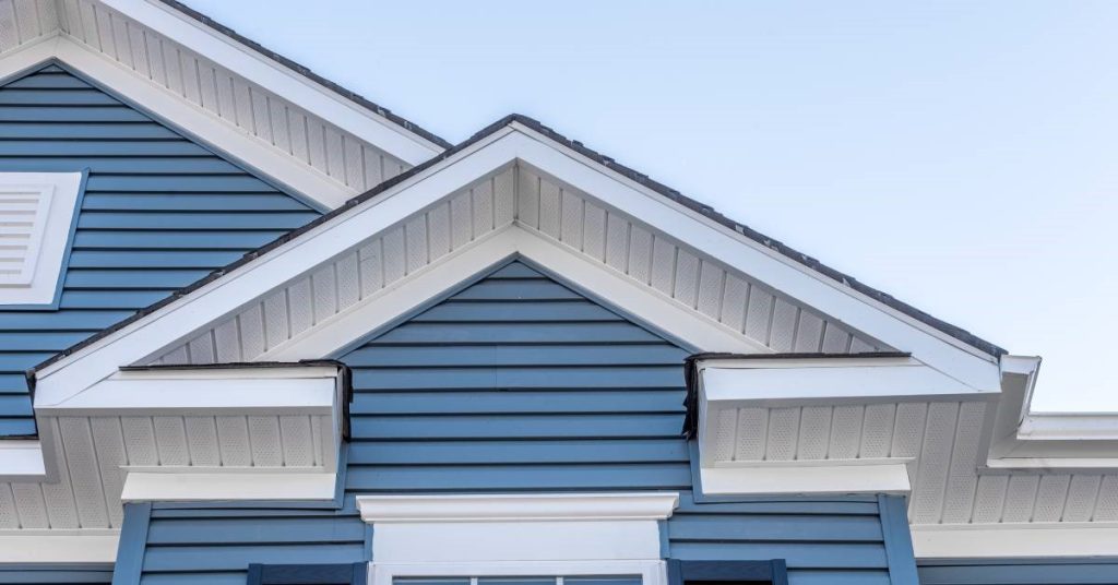 A close-up of the blue vinyl siding and white accents covering the upper levels of a standard residential home.