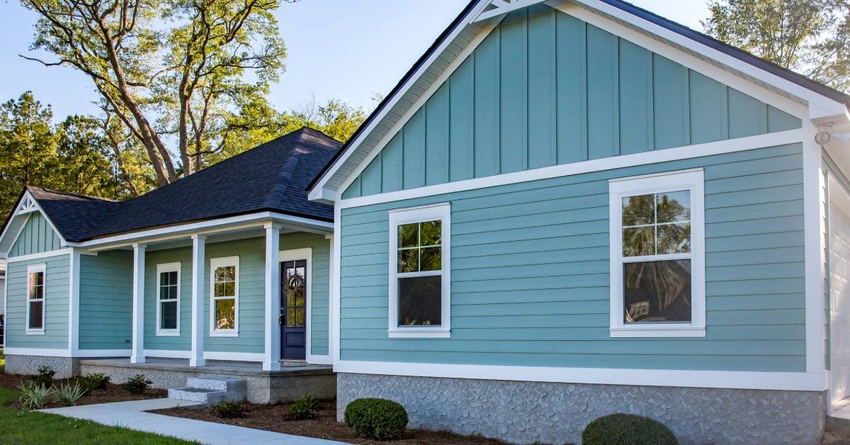 A front view of a ranch-style home featuring light blue vinyl siding with white trim around the windows.