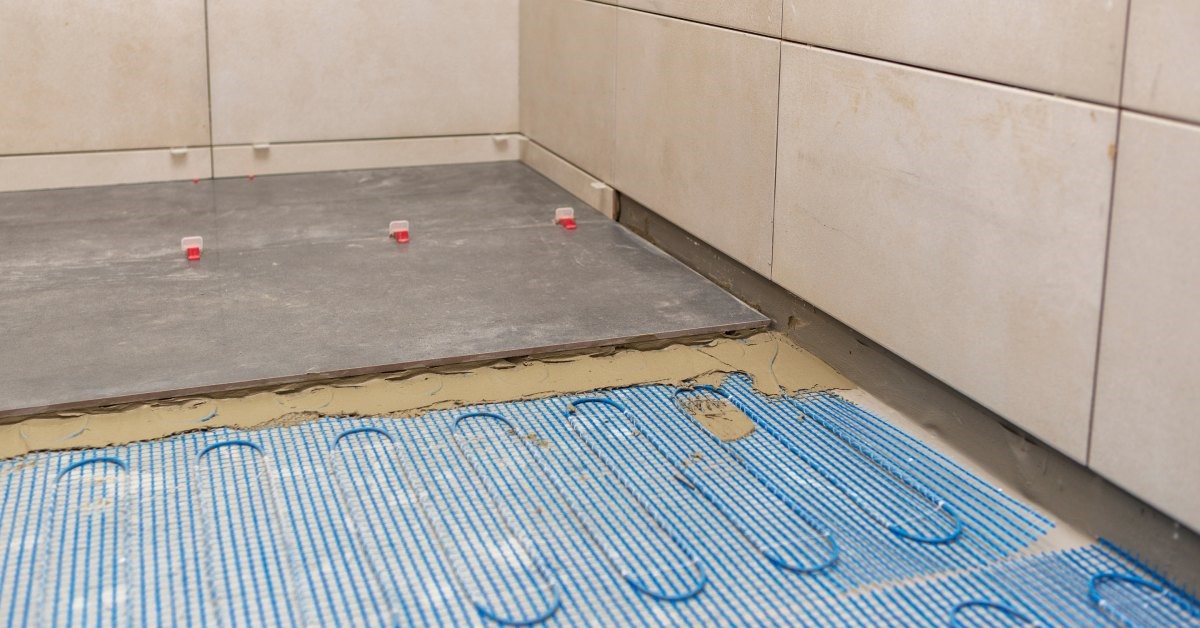 The installation of wires or tubes used to create a radiant heating system under ceramic tiles in a bathroom.