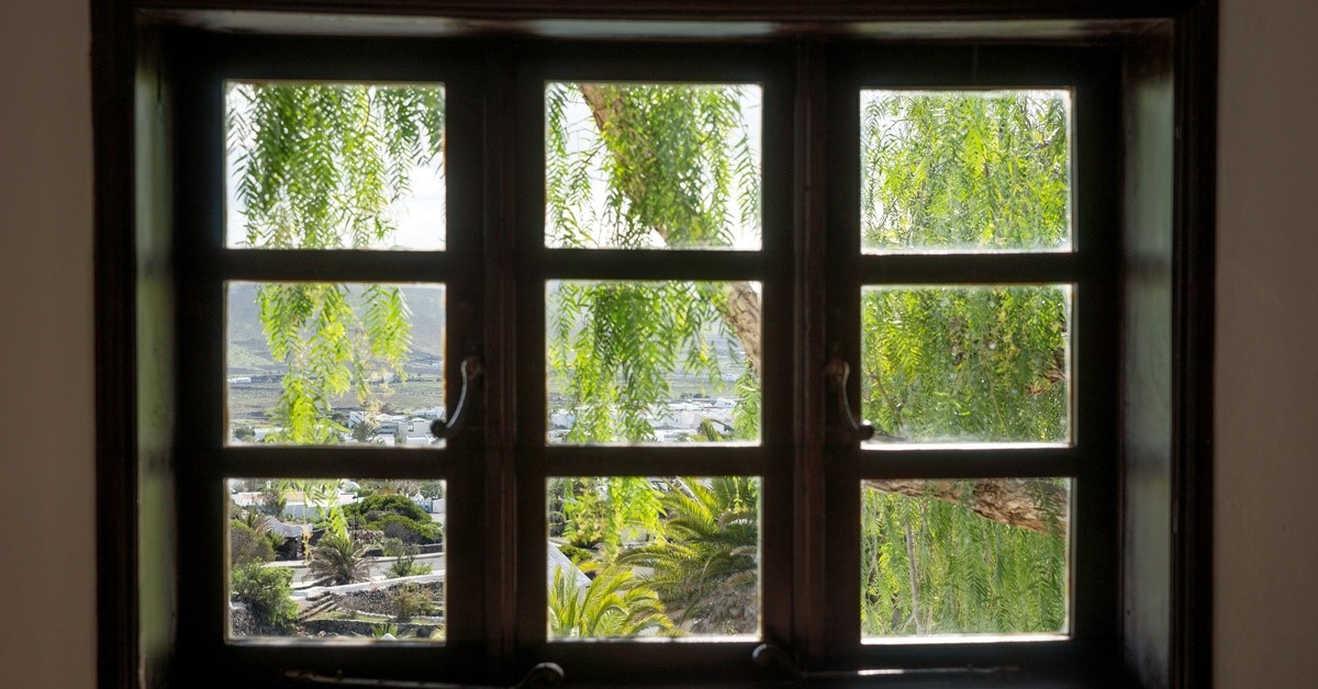 An interior view of a garden window, revealing stunning outdoor views of a garden and the surrounding landscape.