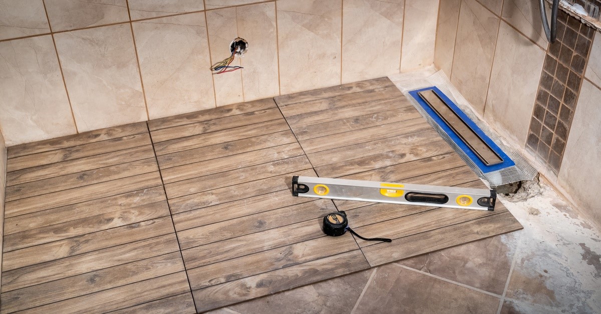 A bathroom undergoing the installation of a new shower. The shower has ceramic tiles with a wooden effect.