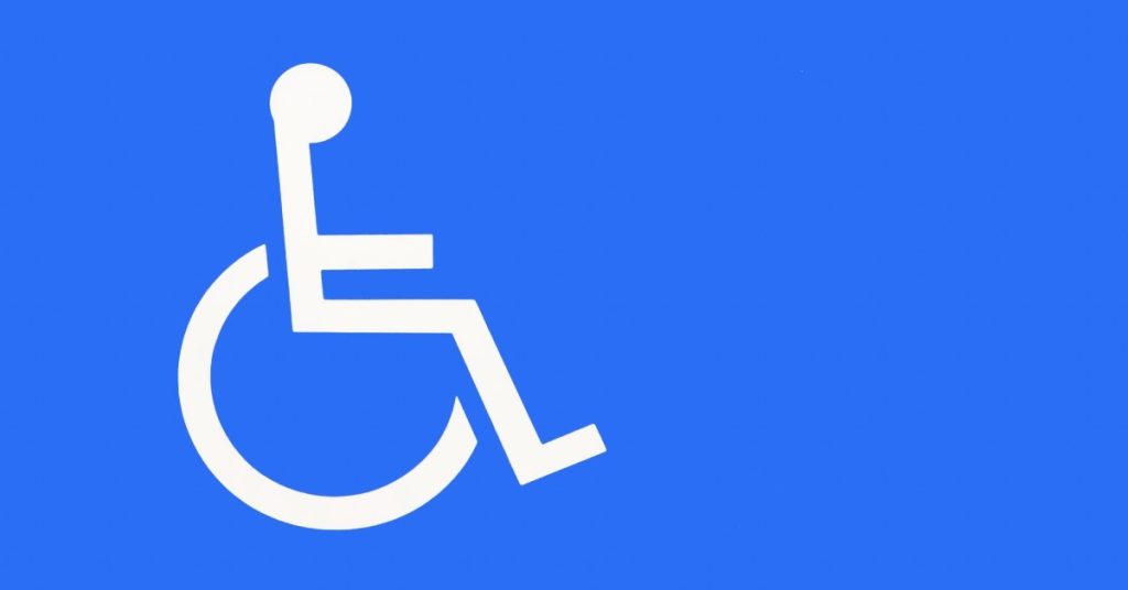 A white icon depicting a stick person sitting in a wheelchair against a large plain blue background.