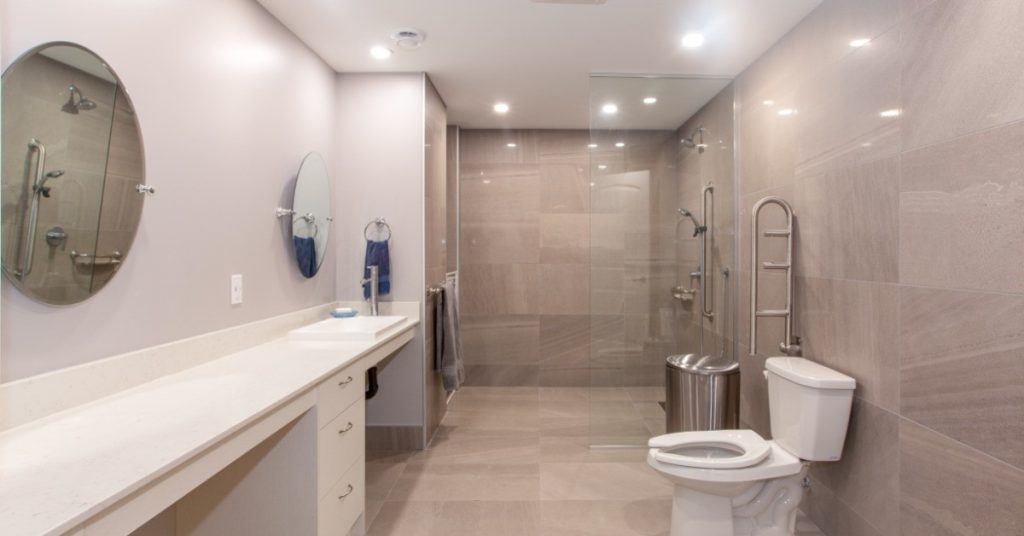 A bathroom with a toilet to the right side of the frame and a roll-in shower at the far end of the room.